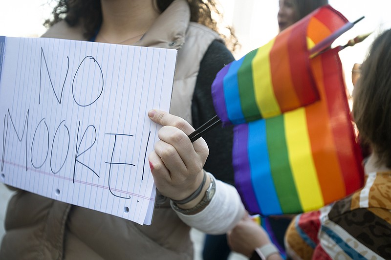 Claire Shimberg holds rainbow flags and a sign on a note pad during a rally against Alabama Chief Justice Roy Moore on Tuesday, Jan. 12, 2016, outside the Alabama Supreme Court building in Montgomery, Ala. Supporters of gay marriage rallied Tuesday against Moore and his opposition to same-sex marriage.