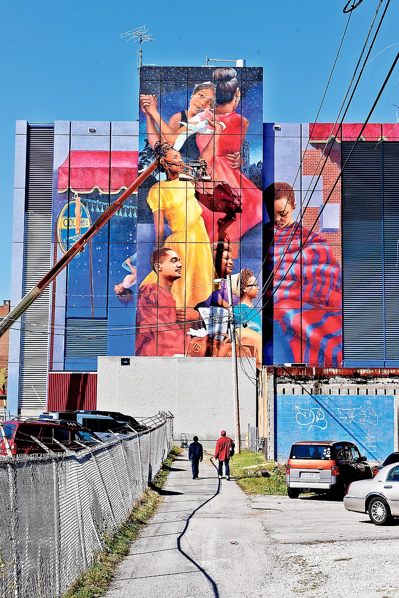 Hollie Berry and Hannah Hahn descend in a 120- foot lift truck after adding the face of Bessie Smith, top center, on the M.L. King Mural.