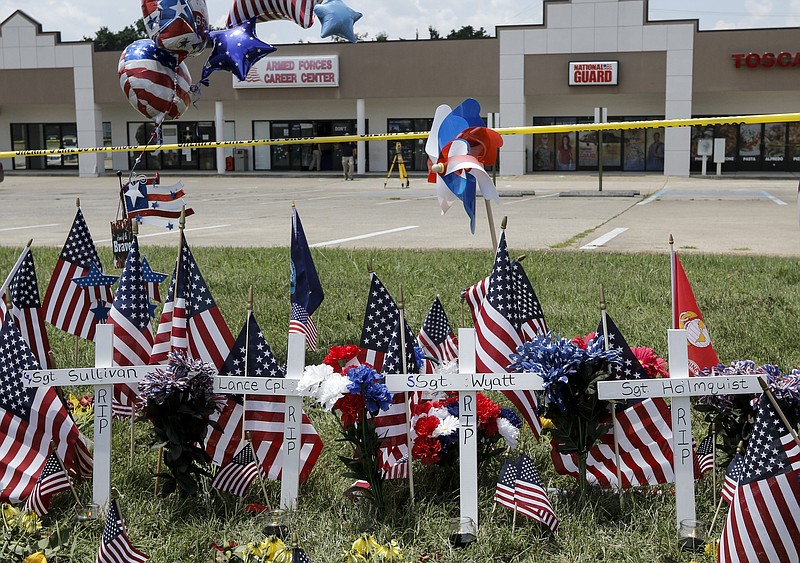 Four crosses are staked in the ground at a Lee Highway memorial in front of the Armed Forces Career Center for the first four victims of the July 16 shootings.