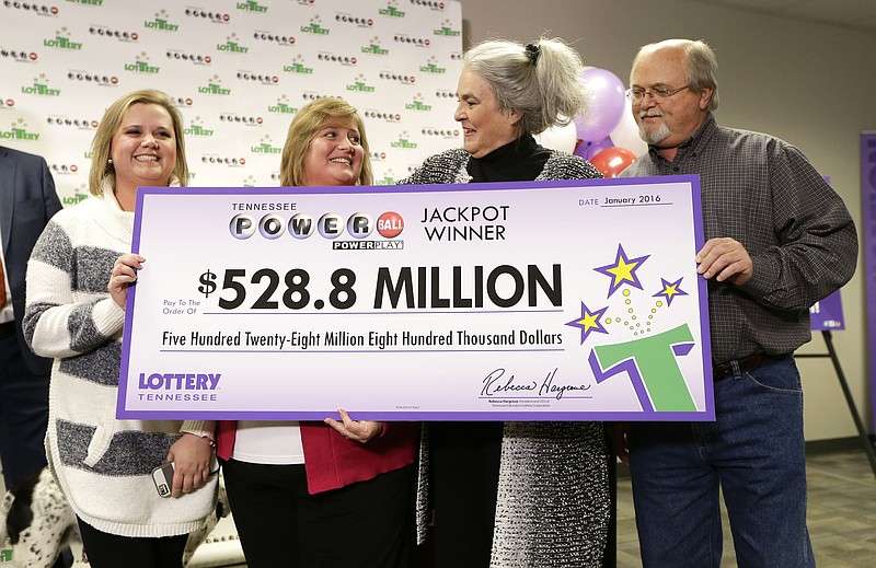 Rebecca Hargrove, second from right, president and CEO of the Tennessee Lottery, presents a ceremonial check to John Robinson, right; his wife, Lisa, second from left; and their daughter, Tiffany, left; after the Robinson's winning Powerball ticket was authenticated at the Tennessee Lottery headquarters Friday, Jan. 15, 2016, in Nashville. The ticket was one of three winning tickets in the $1.6 billion jackpot drawing.