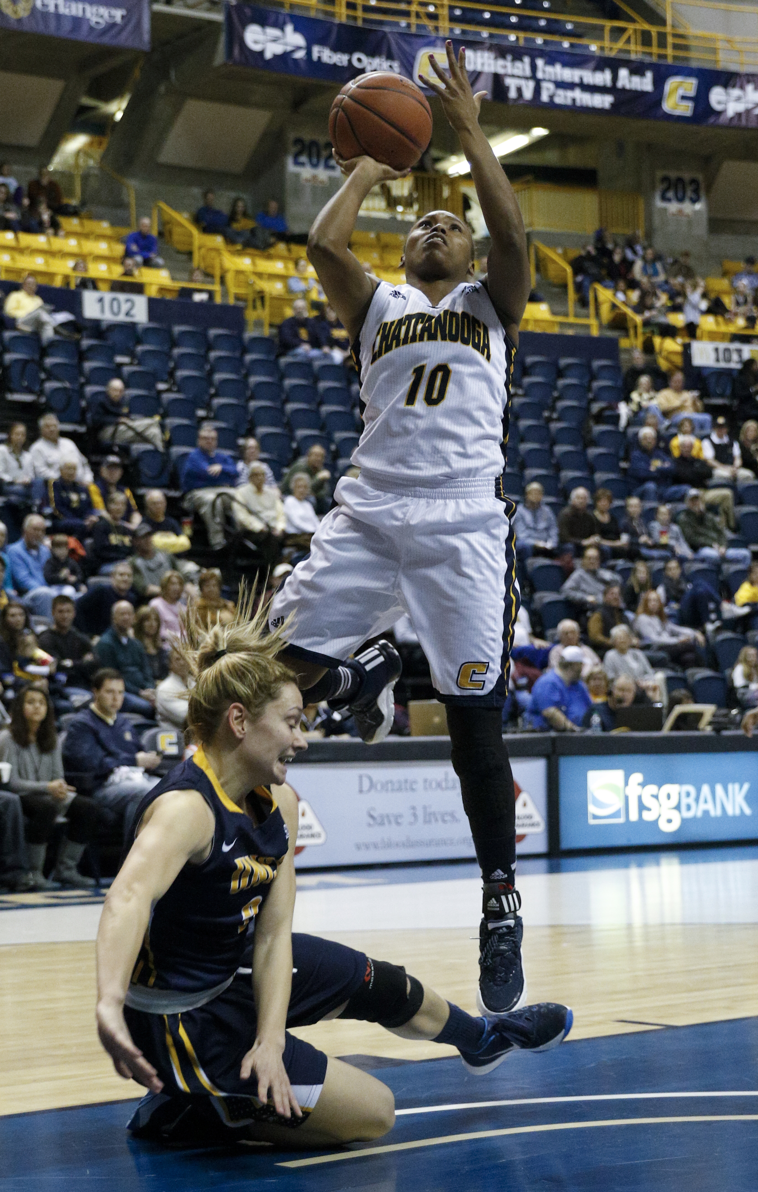 UTC guard Queen Alford (10) shoots as UNCG guard Kaitlin Callahan goes down on the court during the Mocs' home basketball game against UNC-Greensboro at McKenzie Arena on Saturday, Jan. 16, 2016, in Chattanooga, Tenn.