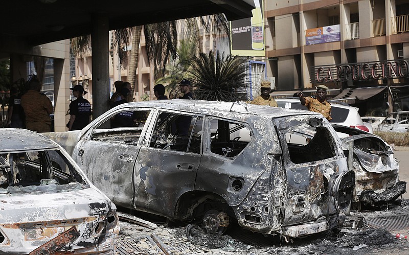 
              Soldiers gesture as they walk past burnt cars outside the Cappuccino cafe that was attacked Saturday by suspected militants in Ouagadougou, Burkina Faso, Sunday, Jan. 17, 2016. The overnight seizure of a luxury hotel in Burkina Faso's capital by al-Qaida-linked extremists ended Saturday when Burkina Faso and French security forces killed four jihadist attackers and freed more than 126 people, the West African nation's president said. (AP Photo/Sunday Alamba)
            