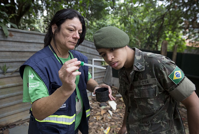 
              A health agent from Sao Paulo's Public health secretary shows an army soldier Aedes aegypti mosquito larvae that she found during clean up operation against the insect, which is a vector for transmitting the Zika virus, in Sao Paulo, Brazil, Wednesday, Jan. 20, 2016. A U.S. warning urging pregnant women to avoid travel to Latin American countries where the mosquito-borne virus is multiplying threatens to depress tourism to the region, one of its few bright spots at a time of deep economic pain.  (AP Photo/Andre Penner)
            