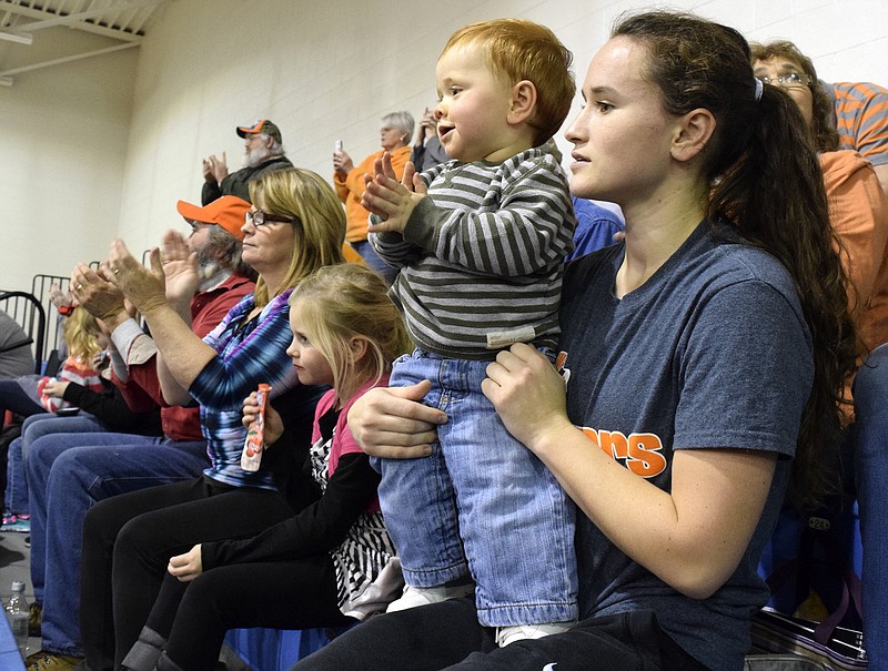 Meigs County basketball player Megan Lewis holds her son Zaelem Ballew during the Meigs County/Polk County boys basketball game.  In the background other members of the Lewis Family cheer on the Tigers.  The Meigs County Tigers visited the Polk County Wildcats in girls and boys TSSAA basketball action January, 19, 2016 in Benton, Tennessee.