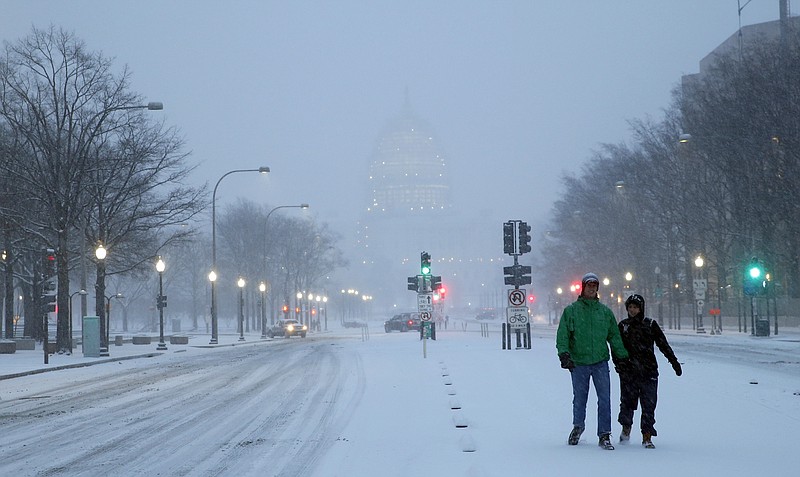 
              Madison Riley, left, and Katie Lantuh walk down the middle of Pennsylvania Avenue with the U.S. Capitol behind them, as the snow falls, Friday, Jan. 22, 2016 in Washington. One in seven Americans will get at least half a foot of snow outside their homes when this weekend's big storm has finished delivering blizzards, gale-force winds, whiteout conditions and flooding to much of the eastern United States. (AP Photo/Alex Brandon)
            