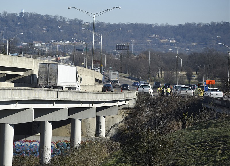TDOT workers, center right, prepare to clear away brush and debris from an I-24 overpass in between Broad Street and the Highway 27 split on Sunday, Jan. 24, 2016, in Chattanooga, Tenn. According to TDOT, one eastbound lane will be closed until bridge workers can make repairs after workers fixing potholes found a broken deck panel and slab on the bridge.