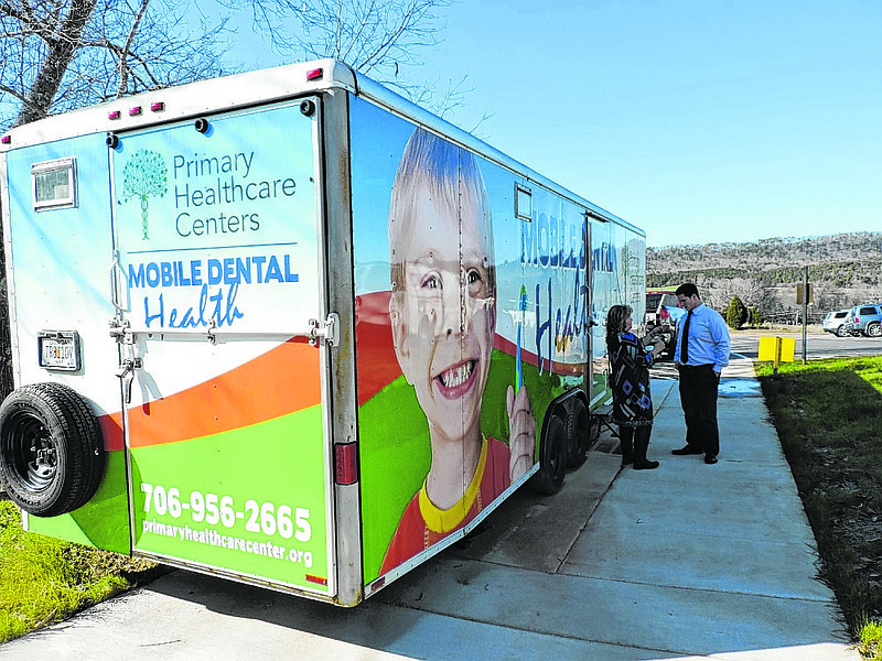 Primary Healthcare Centers' mobile dental health unit sits beside Gilbert Elementary School. In front of the new mobile unit are Primary Healthcare Centers Community Liaison/Director of Community Relations and Development Sandy Matheson, left, and GES Principal Matt Harris.