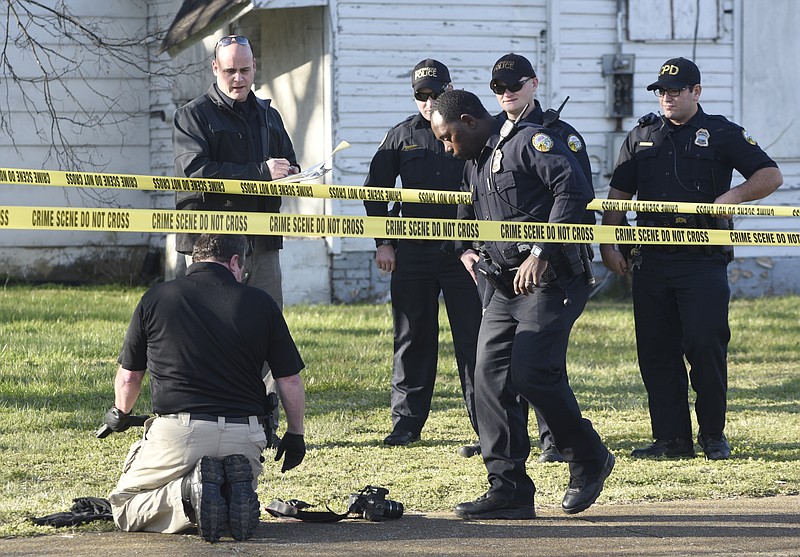 Chattanooga police look at a gun and ammunition clip near the scene of a deadly shooting Monday near the intersection of Orchard Knob and Citico Avenues.