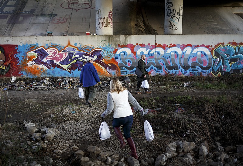 Alex Johnson, Shauna Webb, and Sam Wolfe, from left, carry bags of necessities to a homeless camp beneath I-24 during the annual point-in-time count of the homeless on Wednesday, Jan. 27, 2016, in Chattanooga, Tenn. Volunteers and service providers traveled around the greater Chattanooga area to survey the homeless population in order to better provide services.