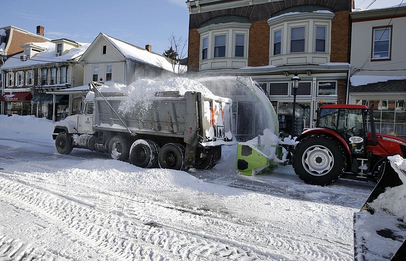 Workers use heavy equipment to remove piles of snow from last weekend's storm, Monday, Jan. 25, 2016, in Newtown, Pa. Pennsylvanians are digging out from the major snowstorm that crippled a stretch of the turnpike and finding many offices and schools closed.
