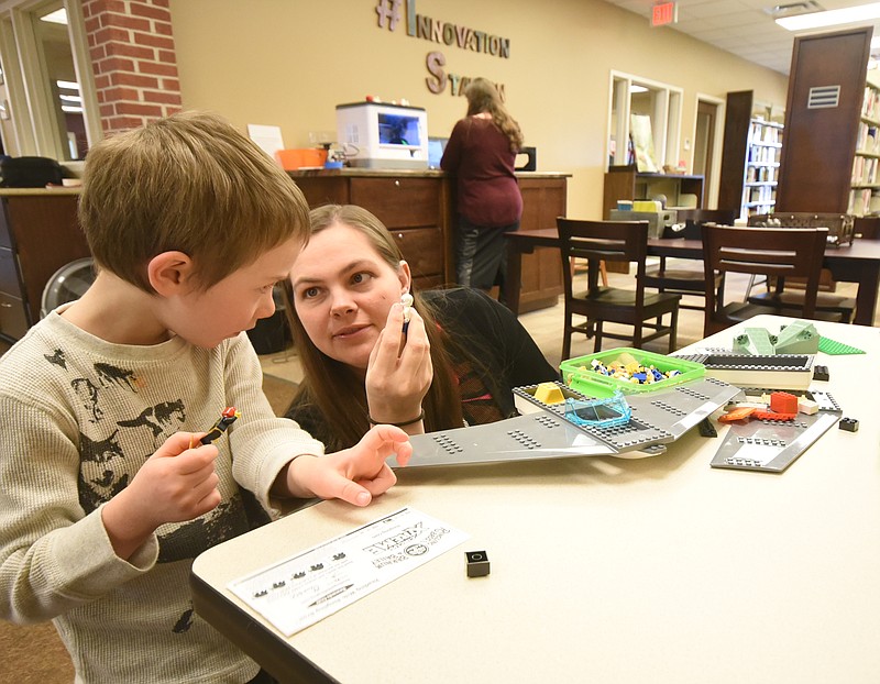 Dade County Public Library Youth Education Coordinator Tasha Denton, right, offers a small Lego character to R.J. Burick, 4, Friday afternoon near the front desk in Trenton, Ga.