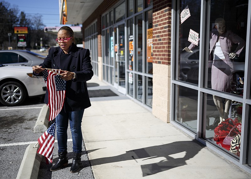 Sonja Wade, whose sister owns Jane of Trades Upscale Resale Shop on Wilcox Boulevard, puts flags on the curb in front of the shop Friday, Jan. 29, 2016, in Chattanooga, Tenn. The Wilcox tunnel remains closed for maintenance, and some Wilcox Boulevard businesses have expressed concerns about the continued closure's effect on their business.