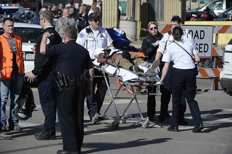 Paramedics transport a man to an awaiting ambulance at the National Western Complex, Saturday, Jan. 30, 2016, in Denver. Denver police say multiple people were injured in a deadly stabbing and shooting at The Colorado Motorcycle Expo. (Andy Cross/The Denver Post via AP)