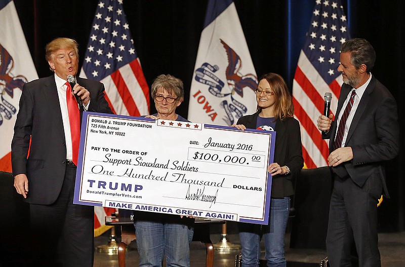 Republican presidential candidate Donald Trump, left, presents a check to members of Support Siouxland Soldiers during a campaign event at the Orpheum Theatre in Sioux City, Iowa, Sunday, Jan. 31, 2016. Also pictured is Jerry Falwell, Jr., right, president of Liberty University. (AP Photo/Patrick Semansky)