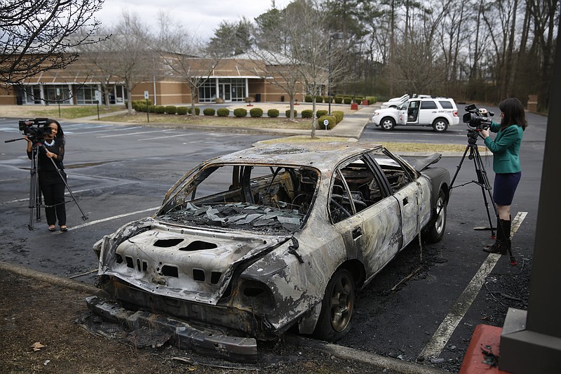 Members of the media videotape a burned car at the Jewish Cultural Center in Chattanooga on Sunday.