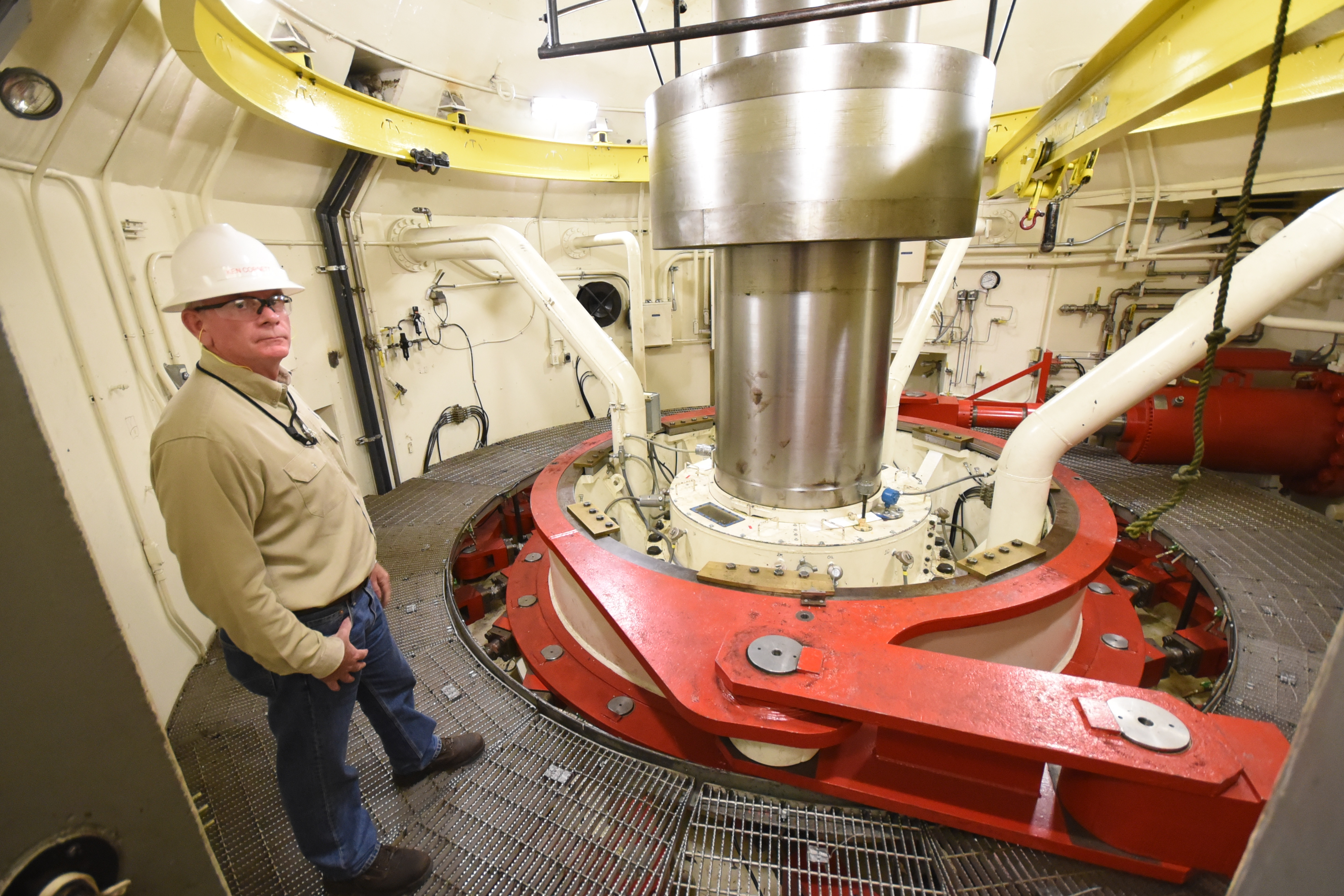 A model deep shows a cutaway of the hydroelectric generators at TVA's pumped storage plant. The very top holds the stator and rotor coils, or the magnetic field in which a coil of wire spins, creating an alternating current of electricity. The hydro-generators are three-phase AC. They switch the phases to make the generators run backwards to pump the water back up to the top. Plant manager Ken Cornett stands near the generator shaft. The bottom-most part of the hydroelectric generator holds the water wheel that spins one way to generate power when it's needed during peak demand, and reverses to pump water from the Tennessee River uphill into the Raccoon Mountain reservoir when demand is low.