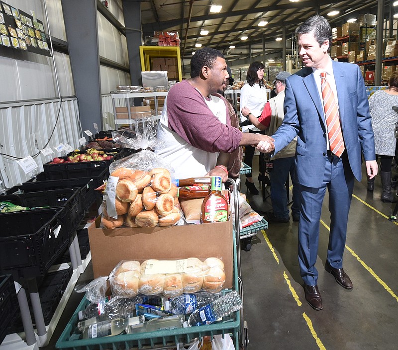 Mayor Andy Berke, right, shakes the hand of Jeshua Johnson as he leaves the Chattanooga Area Food Bank on Tuesday morning. The city of Chattanooga is purchasing 250 food vouchers specifically for families in the 37404 and 37406 areas of town. Donations of $1 will provide four meals, according to Mayor Andy Berke.