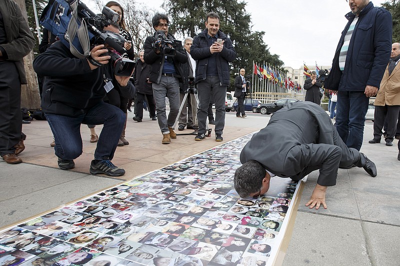 
              Syria's High Negotiations Committee, HNC, spokesman Salem al-Mislet kisses pictures of the Syrian victims of the war displayed in front of the European headquarters of the United Nations, in Geneva, Switzerland, Tuesday, Feb. 2, 2016, where Syria peace talks continue. (Salvatore Di Nolfi/Keystone via AP)
            