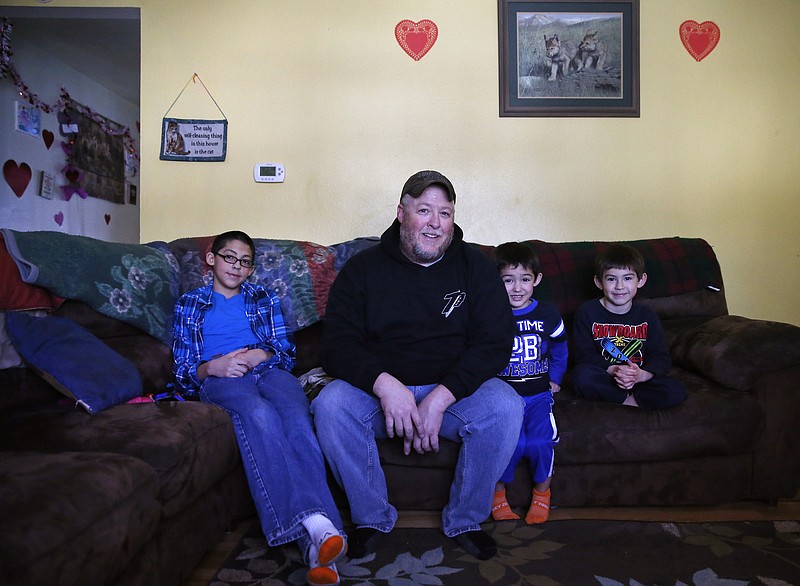 
              Army veteran and current railroad company mechanic Chris Pandolfi sits with his sons, left to right, Joe, 11, Patrick, 4, and Nick, 5, at the home he shares with his wife and their five children, in the community of Security-Widefield, south of Colorado Springs, Colo., Friday Feb. 5, 2016. Compounds called PFOS and PFOA, once used in non-stick cookware coatings, firefighting foam and other materials, were detected in utilities that serve about 69,000 people in the city of Fountain and the adjacent unincorporated Security-Widefield, the federal Environmental Protection Agency said. “I don’t know what the short-term effects are or the long-term effects,” says Pandolfi. (AP Photo/Brennan Linsley)
            