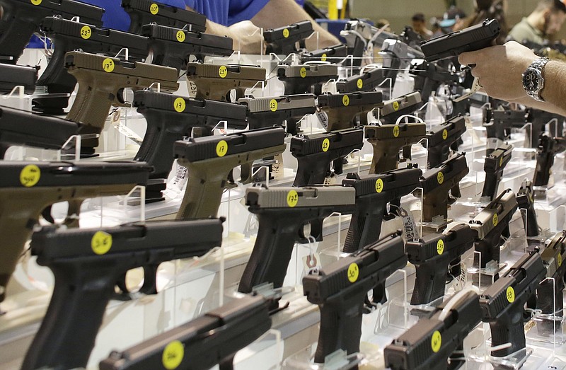 FILE - A customer looks at a pistol at a vendor's display at a gun show held by Florida Gun Shows in Miami on Saturday, Jan. 9, 2016. States enter data into the national background check system about people who are convicted of crimes that disqualify them from buying guns. That information turns up when licensed dealers conduct background checks and has resulted in more than 120,000 applicants being denied since 1998 for having misdemeanor domestic violence convictions. (AP Photo/Lynne Sladky)