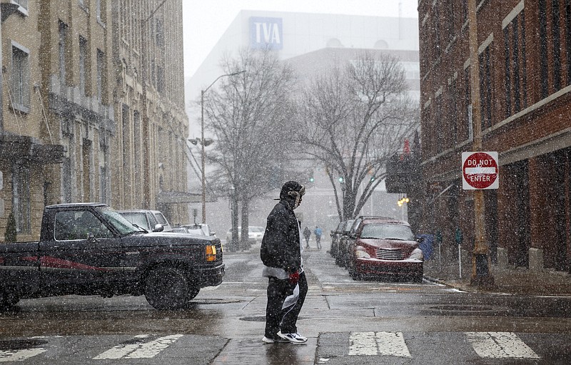 A pedestrian crosses Georgia Avenue during afternoon snow flurries Tuesday, Feb. 9, 2016, in Chattanooga, Tenn.