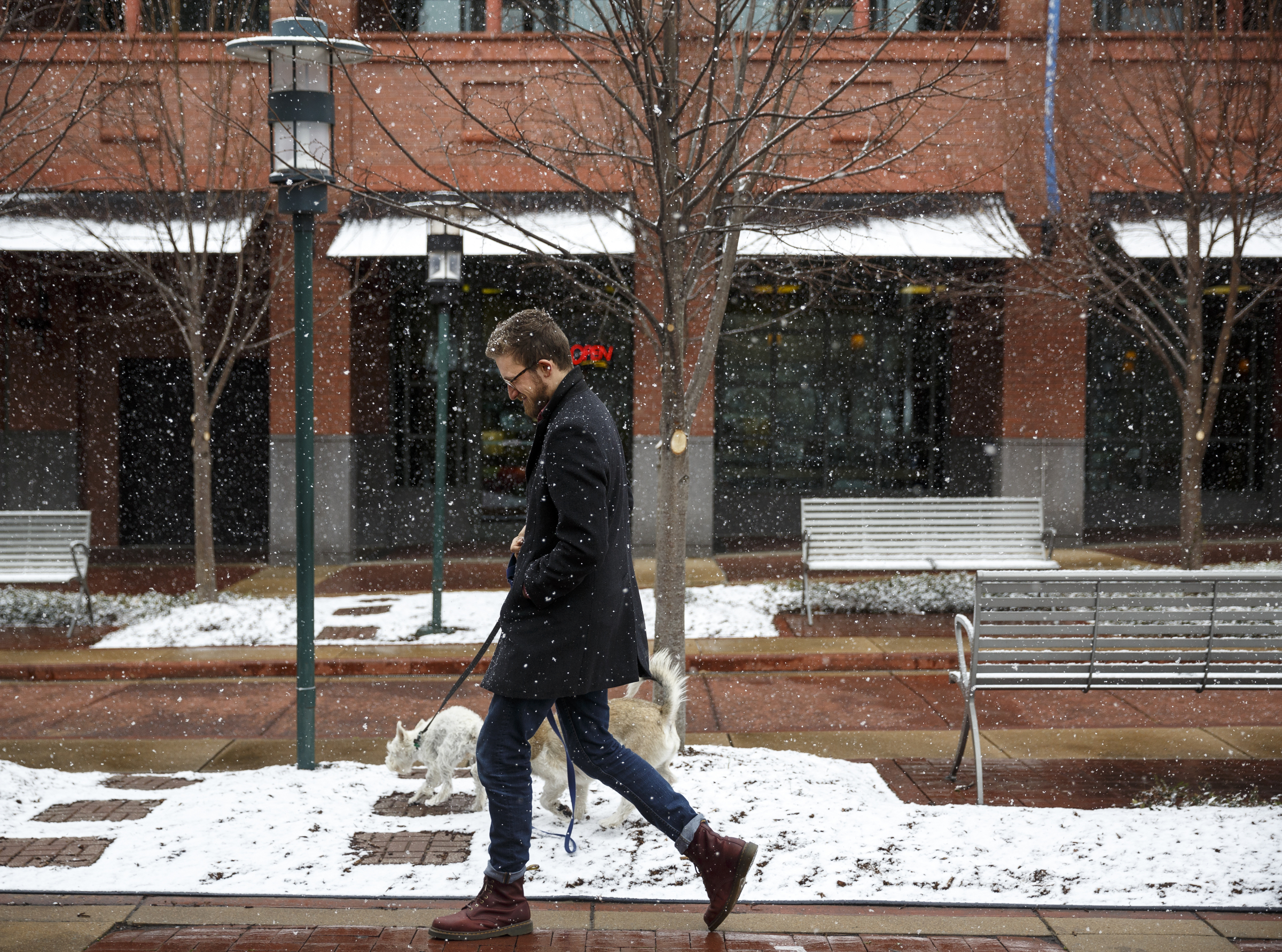 Isaiah Smallman walks his dogs through Miller Plaza during afternoon snow flurries Tuesday, Feb. 9, 2016, in Chattanooga, Tenn.