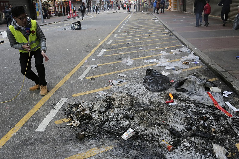 
              A man does a live report, showing the debris after rioters set fires on streets in Mong Kok district of Hong Kong, Tuesday, Feb. 9, 2016. Hong Kong's Lunar New Year celebration descended into chaotic scenes as protesters and police, who fired warning shots into the air, clashed over a street market selling fish balls and other local holiday delicacies, leaving dozens injured and arrested. (AP Photo/Vincent Yu)
            