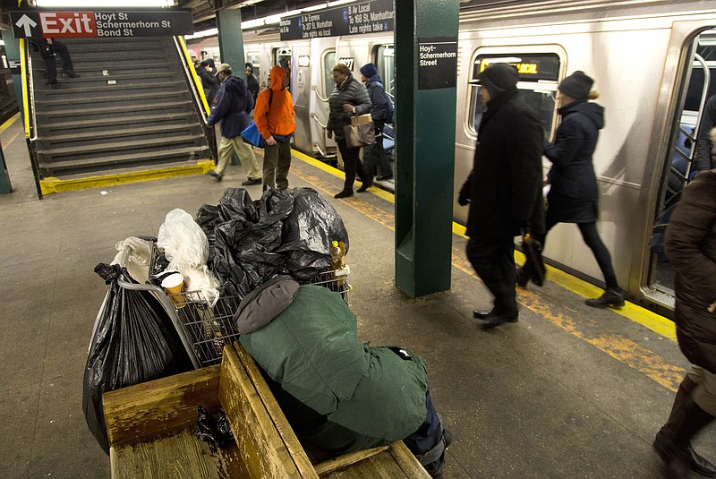 
              Subway riders walk past a homeless person sleeping on a bench, Tuesday, Feb. 9, 2016, at the Hoyt-Schermerhorn Street station in the Brooklyn borough of New York. As cities nationwide undertake a census of homeless people, perennial concerns arise over the count's reliability. New York City's count took place in freezing weather. (AP Photo/Mark Lennihan)
            