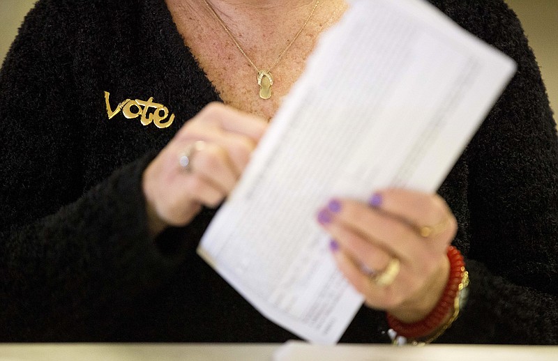 
              A "vote" pin decorates the sweater of ward clerk Lynn Lavigne as she opens absentee ballots for the New Hampshire primary, Tuesday, Feb. 9, 2016, at a polling place in Manchester, N.H. (AP Photo/David Goldman)
            