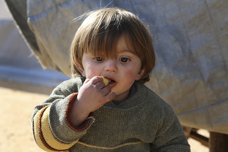 
              In this photo provided by Turkish Islamic aid group IHH, a displaced Syrian boy eats at a temporary refugee camp in northern Syria, near Bab al-Salameh border crossing with Turkey, Monday, Feb. 8, 2016. Turkey was under pressure from the EU to open its border to up to 35,000 Syrians who have massed along the frontier in the past few days fleeing an onslaught by government forces and intense Russian airstrikes  in Aleppo. (IHH via AP)
            