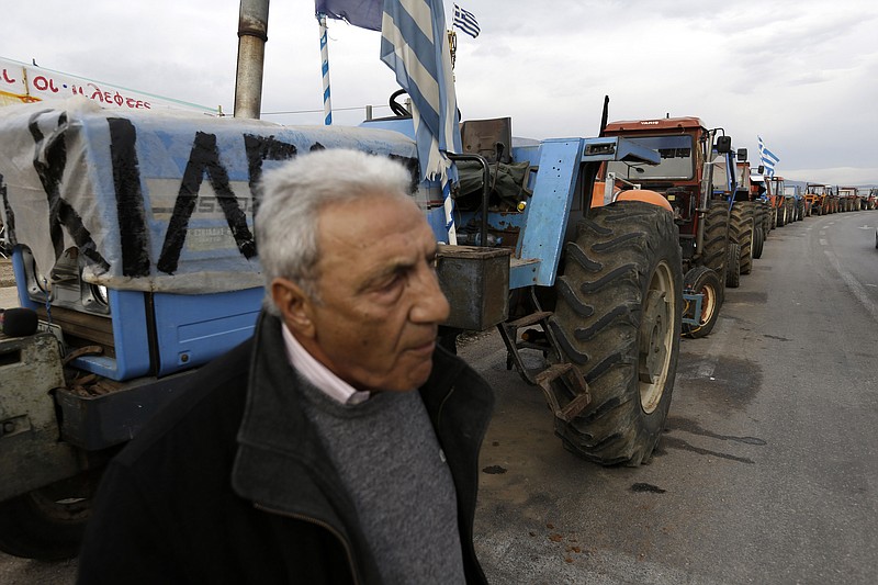 
              A farmer walks by a line of tractors parked in protest at a vital point, on a road that links the international airport with the southern and eastern suburbs of the Greek capital, in Koropi, near Athens, Wednesday, Feb. 10, 2016. Farmers in northern Greece have blocked traffic on the country's main highway, intensifying nationwide protests against austerity measures demanded by bailout lenders. (AP Photo/Thanassis Stavrakis)
            