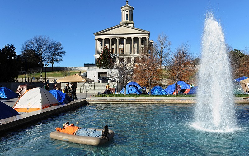 In this 2011 file photo, Occupy Nashville protestor Duncan McAfee relaxes on an air mattress after checking it for leaks in a fountain at Legislative Plaza in Nashville, Tenn.