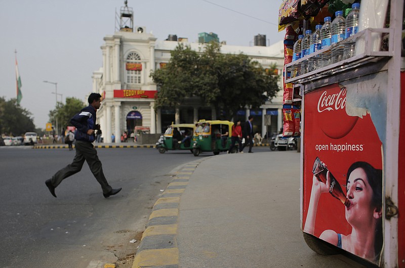 
              An Indian pedestrian crosses a road near roadside kiosk with a Coca-cola advertisement in New Delhi, India, Friday, Feb. 12, 2016. Coca-Cola suspended bottling at three plants in India, including one in the parched northwest where farmers have been protesting the company's use of dwindling groundwater reserves. (AP Photo/Altaf Qadri)
            