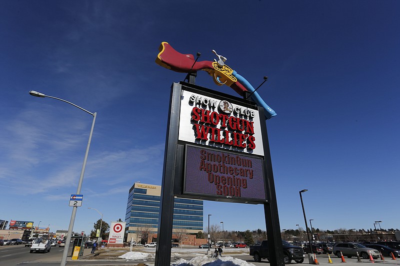 
              In this Feb. 10, 2016 photo, a large roadside sign marks the entrance of longtime strip club Shotgun Willie's, and Smoking Gun Apothecary, the new marijuana dispensary, in Glendale, Colo.   Smokin Gun Apothecary is on a site formerly occupied by the Denver area’s best known strip club, Shotgun Willie’s. The strip club hasn’t gone away, it’s moved just across the parking lot. Both businesses have the same owner, who envisions pot shoppers getting discounted drinks at the strip club and is outfitting the roof of the pot shop for a future lounge in case Colorado changes its law banning on-site marijuana consumption.(AP Photo/Brennan Linsley)
            