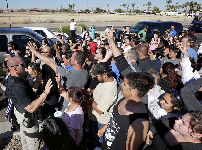 
              A Phoenix police officer, left, tries to give instructions to parents waiting to reunite with their children, Friday, Feb. 12, 2016, in Glendale, Ariz. after two teens were shot Friday at Independence High School in the Phoenix suburb.   Glendale Officer Tracey Breeden told reporters Friday that both victims were 15 years old and were shot once. She says authorities are not searching for any suspects and a weapon was found near the bodies. Breeden told parents awaiting word on their kids that "your children are safe." (AP Photo/Matt York)
            