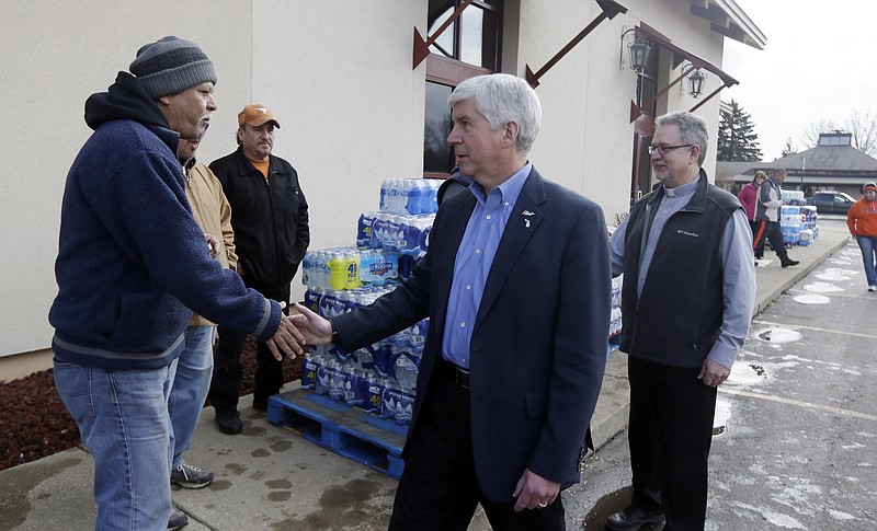 
              HOLD FOR STORY BY DAVID EGGERT- FILE- In a file photo from Feb. 5, 2016, Michigan Gov. Rick Snyder, center and Our Lady of Guadalupe Church Deacon Omar Odette, right, meet with volunteers helping to load vehicles with bottled water in Flint, Mich. Snyder's standing as one of the GOP's most accomplished governors has taken a beating in the lead-contaminated water emergency in Flint. Democrats, especially those running for president, are pointing to mistakes by Snyder's administration during the crisis as a vivid example of Republican-style cost-cutting run amok. (AP Photo/Carlos Osorio)
            