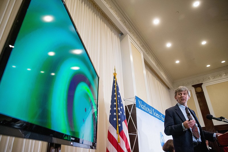 A visual of gravitational waves from two converging black holes is depicted on a monitor as Interferometer Gravitational-Wave Observatory (LIGO) Exectutive Director David Reitze speaks during a news conference at the National Press Club in Washington, Thursday, Feb. 11, 2016, to announce that scientists they have finally detected gravitational waves, the ripples in the fabric of space-time that Einstein predicted a century ago.