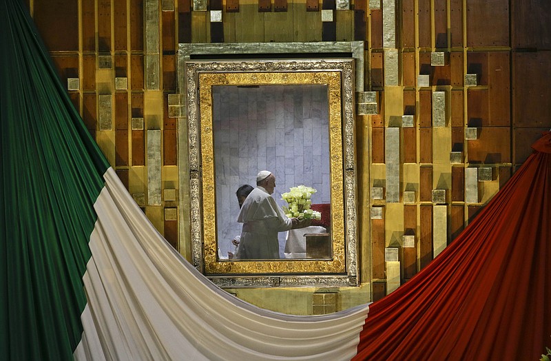 
              Pope Francis, seen on the other side of the framed glass that usually holds the image of the Virgin of Guadalupe, holds a flower bouquet as he prays to her inside a private room at the Basilica built in her honor, during Mass in Mexico City, Saturday, Feb. 13, 2016. The image in the frame was removed and placed inside the private room. The pontiff's five-day visit included a prayer before the Virgin of Guadalupe shrine, the largest and most important Marian shrine in the world and one that is particularly important to the first Latin American pope. (AP Photo/Gregorio Borgia)
            