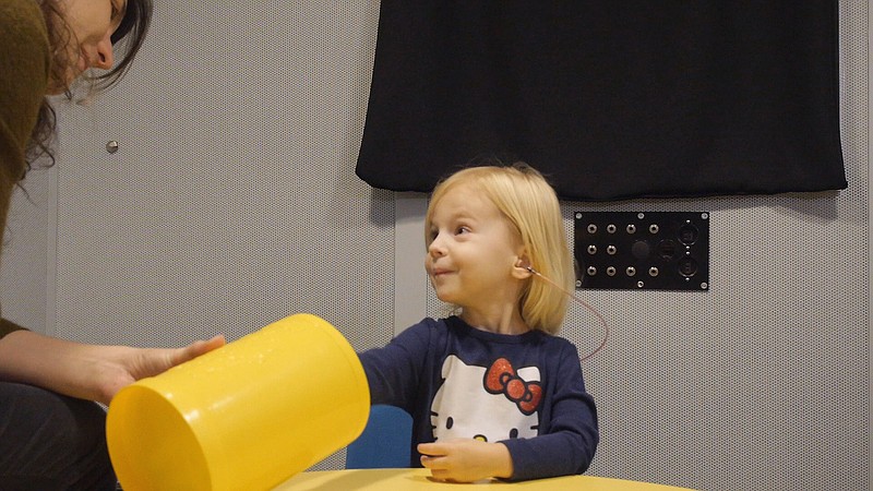 
              In this images from video provided by University of North Carolina at Chapel Hill, a toddler participates in a speech perception experiment in a laboratory at the University of North Carolina in Chapel Hill, N.C.. The toddler was conditioned to put a block in the bucket whenever she heard the “target” word. From the cacophony of day care to the buzz of TV and electronic toys, noise is more distracting to a child's brain than an adult's, and new research shows it can hinder how youngsters learn. In fact, one of the worst offenders when a tot's trying to listen is other voices babbling in the background, researchers said Saturday at a meeting of the American Association for the Advancement of Science. (Emily Buss/University of North Carolina at Chapel Hill via AP)
            