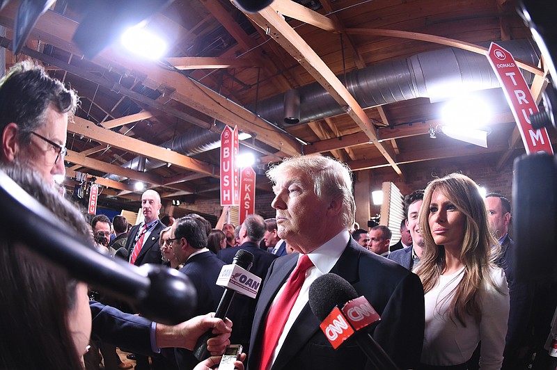 
              Republican presidential candidate, businessman Donald Trump with his wife Melania Trump at right,  speaks to the media in the spin room after the CBS News Republican presidential debate at the Peace Center, Saturday, Feb. 13, 2016, in Greenville, S.C. (AP Photo/Rainier Ehrhardt)
            