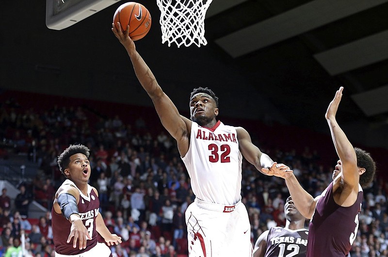 Alabama guard Retin Obasohan, center, scores against Texas A&M guard Admon Gilder, left, and center Tyler Davis, right, during the second half of an NCAA college basketball game, Wednesday, Feb. 10, 2016, in Tuscaloosa, Ala. Alabama won 63-62. (AP Photo/Brynn Anderson)