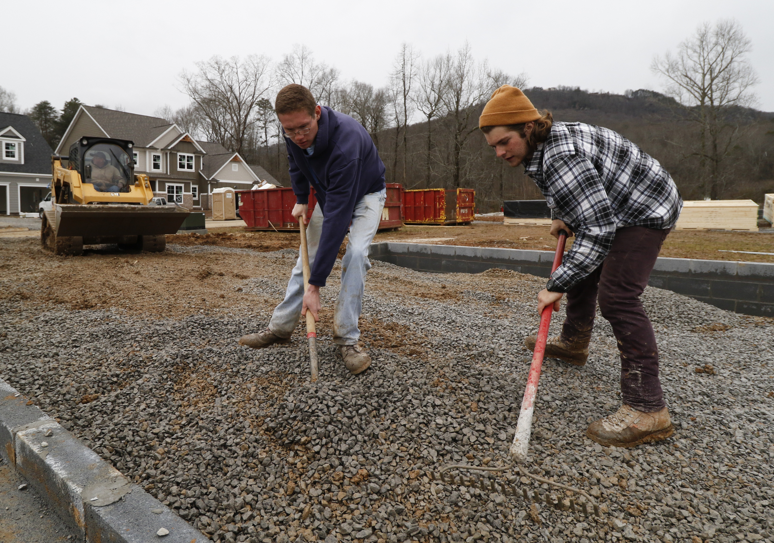 Staff Photo by Dan Henry / The Chattanooga Times Free Press- 2/16/16. Mike Higgins brings a load of gravel as his son Michael Higgins Jr. and employee Collin Heard level gravel while doing site work in preparation to pour a driveway at a new subdivision being developed off of Pitts Road in Hixson on Tuesday, February 16, 2016. Recent precipitation has saturated the ground and caused some area construction projects to be delayed.