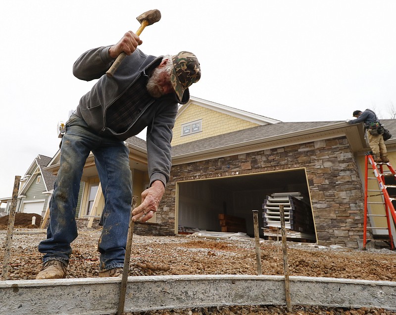Staff Photo by Dan Henry / The Chattanooga Times Free Press- 2/16/16. Marty Campbell hammers in spikes to hold a concrete form while preparing to pour a driveway at a new subdivision being developed off of Pitts Road in Hixson on Tuesday, February 16, 2016. Recent precipitation has saturated the ground and caused some area construction projects to be delayed.