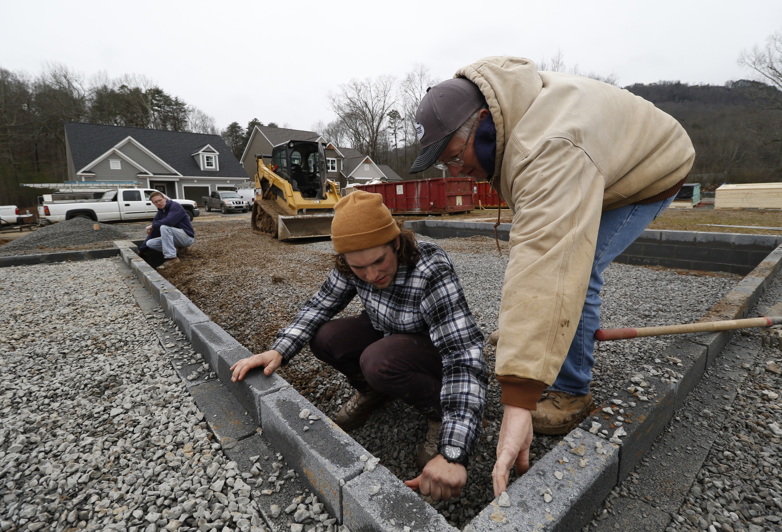 Staff Photo by Dan Henry / The Chattanooga Times Free Press- 2/16/16. Michael Higgins Jr., Collin Heard and Mike Higgins, from left, level gravel while doing site work in preparation to pour a driveway at a new subdivision being developed off of Pitts Road in Hixson on Tuesday, February 16, 2016. Recent precipitation has saturated the ground and caused some area construction projects to be delayed.
