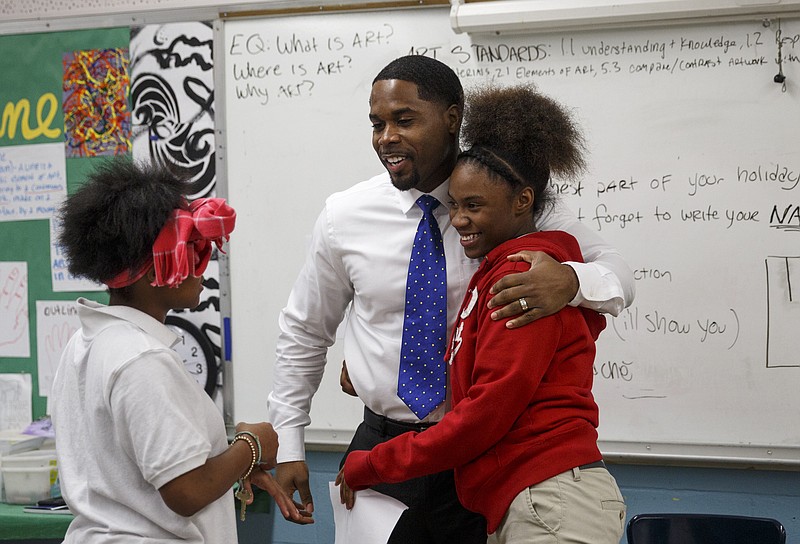 Marcellus Barnes , center, hugs Jessica Newby as he talks with Kalisha Evans before leading students in a choir lesson at Orchard Knob Middle School on Tuesday, Feb. 16, 2016, in Chattanooga, Tenn. Barnes is hosting his 10th annual Sounds of Unity concert in recognition of Black History Month at Abbas House on Feb. 27.