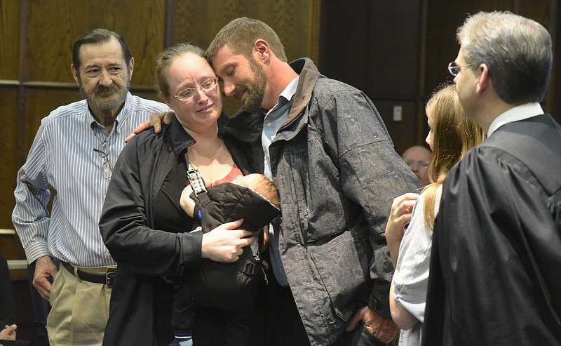 While his father James Womack, left, daughter Jozelen Womack, and Judge Tom Greenholtz watch, graduate Jason Womack, center, hugs his wife Charlene Womack as she holds their two-month-old son Kobra Womack, during Drug Court graduation on Monday, Feb. 22, 2016, in Chattanooga, Tenn. Womack reconciled with his wife and family during his progress through Drug Court. 