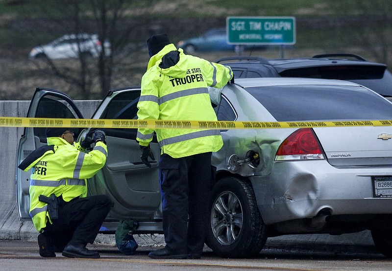 Troopers with the Tennessee Highway Patrol investigate a vehicle at the scene of a crash on Interstate 75 at the East Brainerd Road exit that was the result of the agency's pursuit of rape suspect Cordarius Caldwell on Wednesday, Feb. 24, 2016, in Chattanooga, Tenn. At least 15 vehicles were struck, including patrol cars, and a trooper suffered minor injuries in the chase, which concluded with the arrest of Caldwell, 20, who was wanted for charges of rape and false imprisonment in Nashville.