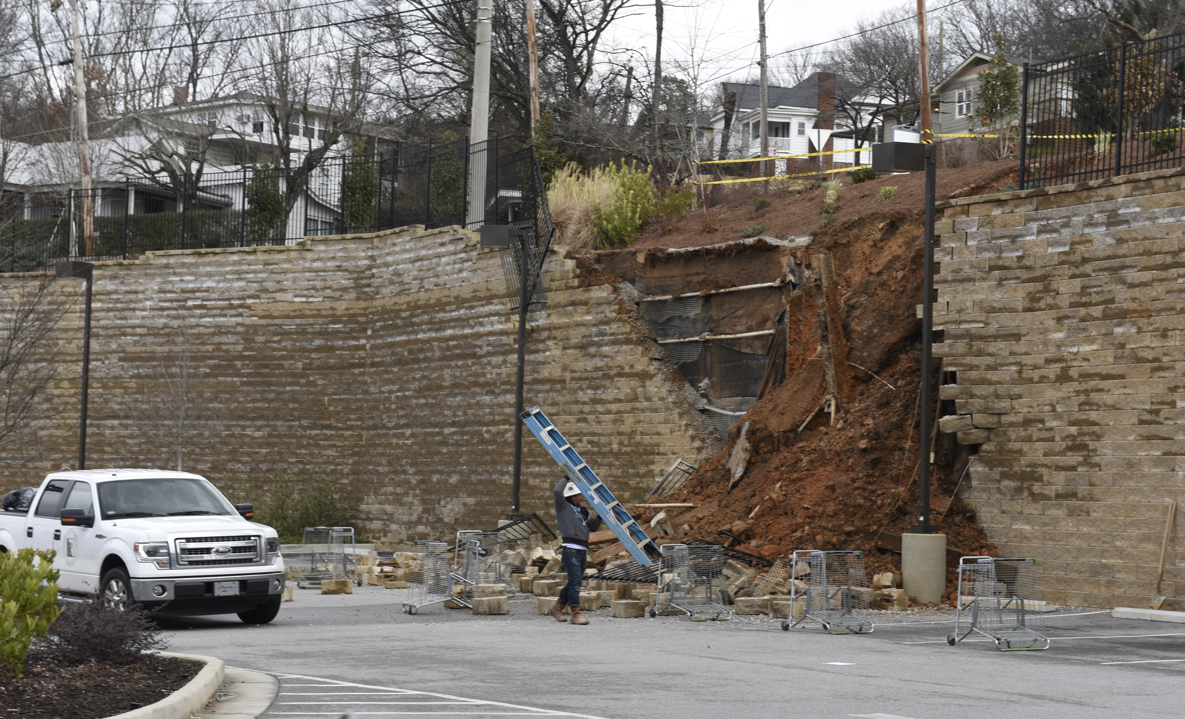 A worker carries a ladder past a collapsed section of wall at a Publix grocery store parking lot in the North Chattanooga community on Thursday morning, Feb. 25, 2016, in Chattanooga, Tenn.