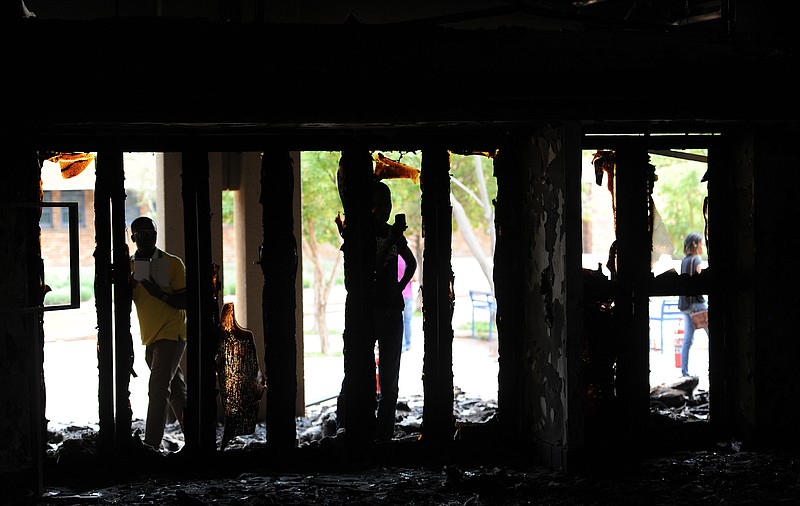 
              Student look through the windows at the remains of the Science Center at the North-West University in Mahikeng South Africa, (also known as Mafikeng) Thursday, Feb. 25, 2016.  Protesting students burned down several buildings on the campus Wednesday forcing the evacuation and indefinite closure till further notice a spokesman said Thursday. (AP Photo)
            