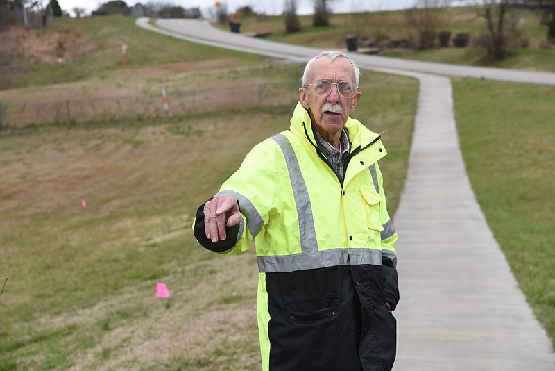 Gene Hyde inspects and talks about planting trees near marked gas lines in the Murray Hills Walking Track park near Highway 58.